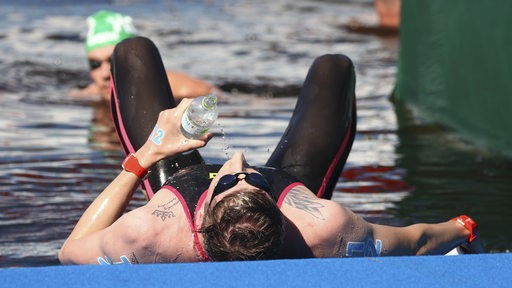 Schwimmer Florian Wellbrock liegt nach seinem Olympia-Sieg über zehn Kilometer im Freiwasser erschöpft am Steg.