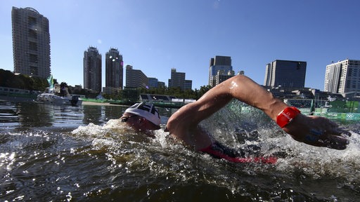 Schwimmer Florian Wellbrock bei seinem zehn Kilometer Rennen im Freiwasser vor der Skyline von Tokio.