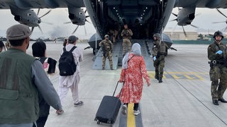 Menschen steigen in ein Militärflugzeug der Luftwaffe in Kabul, Afghanistan.