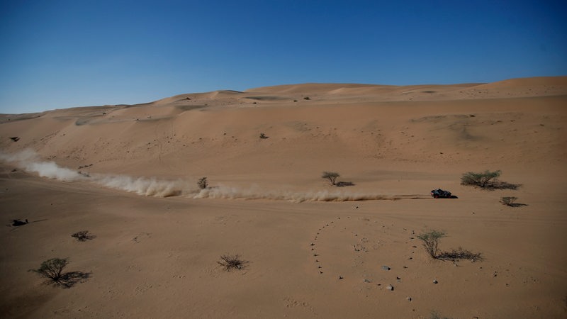 Auto fährt in der Wüste allein auf weiter Sicht bei der Rallye Dakar.