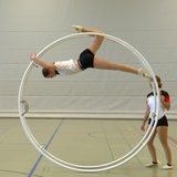Jugendliche turnen mit Rhönrädern in einer Sporthalle.