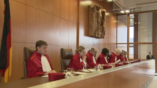 Menschen im Gericht. Sie tragen rote Roben.