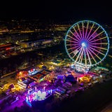 Ein Riesenrad steht im Dunkeln auf einem Jahrmarkt und ist bunt erleuchtet. 