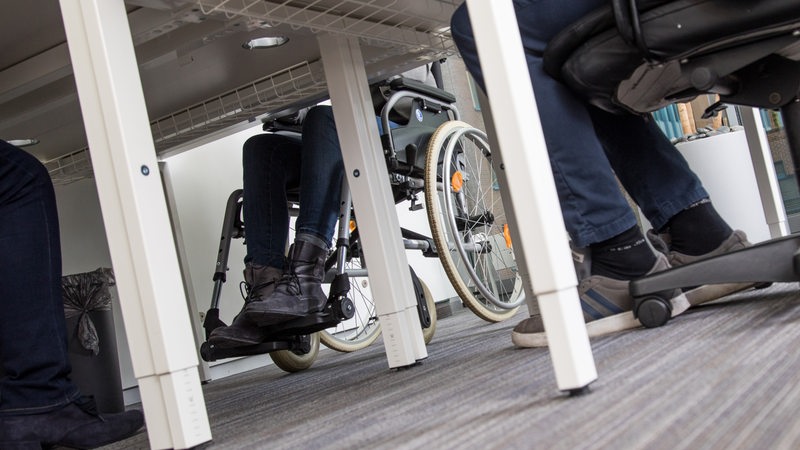 Ein Rollstuhl unter einem Schreibtisch.
