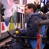 Ein Mann in einem Rollstuhl schaut auf eine vorbeifahrende Bahn.