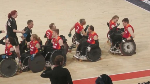 Mehrere Rohlstuhlrugby-Spieler klatschen ab.