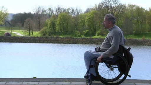 Ein Rollstuhlfahrer fährt an der Weser entlang. 