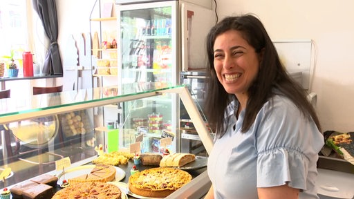 Die Café-Besitzerin Roni Levy steht vor einer Kuchen-Theke.
