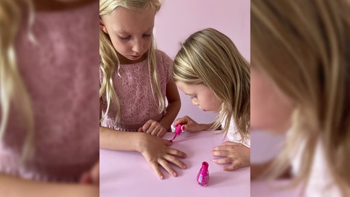 Zwei Mädchen lackieren sich die Fingernägel.
