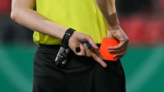 Ein Schiedsrichter zieht eine rote Karte aus seiner Gesäßtasche