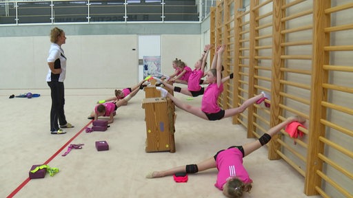 Die jungen Gymnastinnen trainieren am Bundesstützpunkt in Bremen, die Trainerin guckt ihnen zu. 