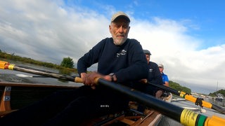 Der Rentner Fritz Benjes sitzt in einem Boot und rudert. 