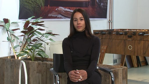Die Autorin und politische Aktivistin Sadaf Zahedi sitzt auf einem Stuhl und blickt in die Kamera.