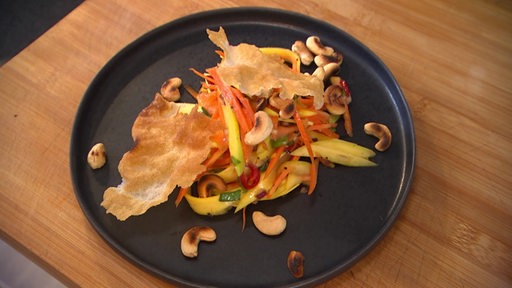 Auf dem Bremer Teller ist ein scharfer Mango-Papaya-Salat mit Cashewkernen zu sehen.