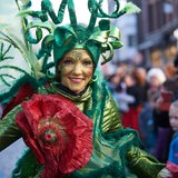 Frau mit grüner Maske und Kostüm beim Samba-Umzug