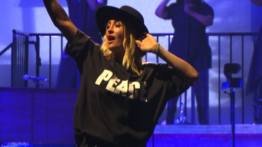 Die Sängerin Sarah Conner performt in Bremen in einem schwarzen T-Shirt mit "Peace"-Aufschrift bei einem Konzert.