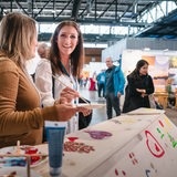 Frau, die Sarg bemalt, lächelt auf einer Messe in die Kamera