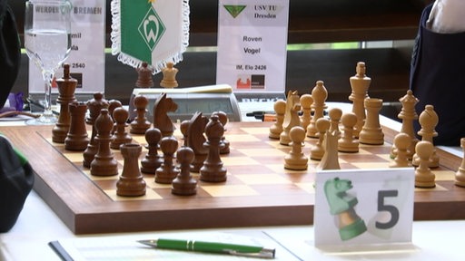 Schachfiguren aus Holz mit Werderflagge im Hintergrund