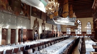 Obere Rathaushalle in Bremen, darin lange Tafeln, eingedeckt für die Schaffemahlzeit.