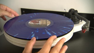 Eine Schallplatte wird auf einen Plattenspieler gelegt.