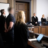 Ein Angeklagter steht zwischen seinen beiden Verteidigern im Gerichtssaal vom Landgericht Verden. 