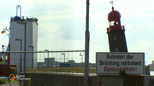 Der schiefe Leuchtturm von Bremerhaven neben einem mit Stroh beladenen Spezialschiff.