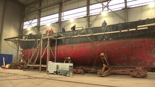 Ein Schiff wird in einer Werfthalle restauriert.