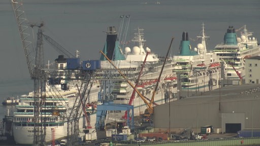 Zu sehen sind mehrere große Schiffe an einem Hafen.