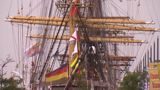 Es sind mehrere Schiffsmasten und Länderflaggen zu sehen.