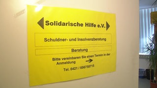 Ein gelbes Schild von "Solidarische Hilfe e.V" an einer Tür.