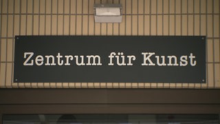 Ein Schild mit der Aufschrift "Zentrum für Kunst" auf braunen Fliesen.