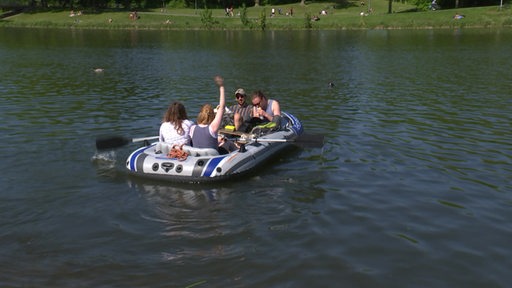 Vier Personen mit Hund genießen in einem Schlauchboot auf dem Werder-See das gute Wetter.