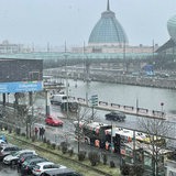 Auf einer nassen Straße fahren Autos im Schneegestöber.