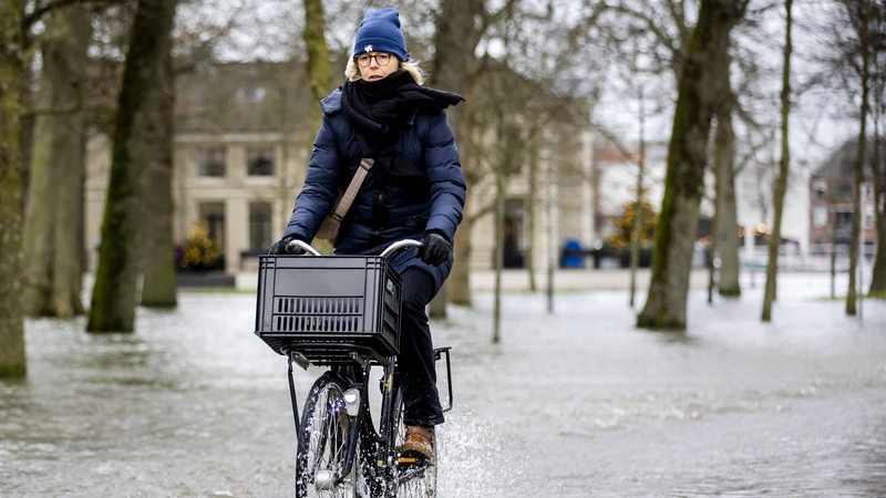 Eine Frau fährt mit dem Fahrrad durch Wasser.