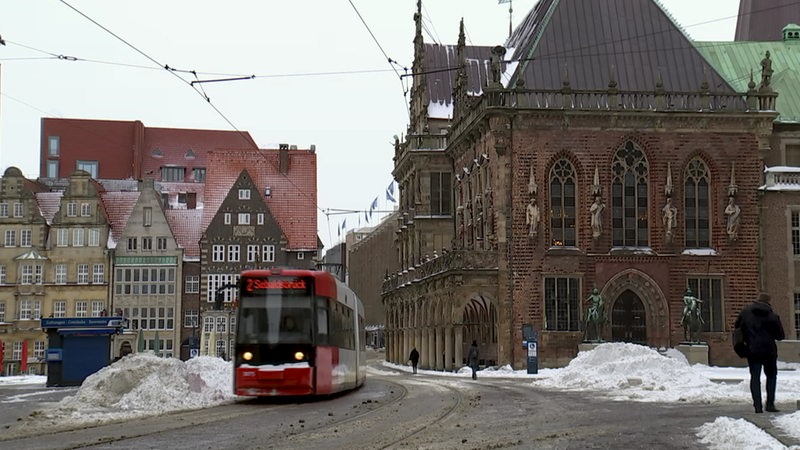 Eine Straßenbahn die in der Bremer Altstadt durchfährt, überall liegt Schnee. 