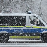 Ein Polizeiwagen fährt auf einer Straße im Schnee.