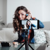 Eine Influencerin zeigt sich beim Schminken. Im Vordergrund das Video auf dem Handy.