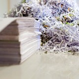 Ein Stapel Zettel und geschreddertes Papier liegen nebeneinander.