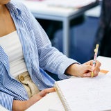 Eine Frau schreibt mit einem Stift in ihr Buch