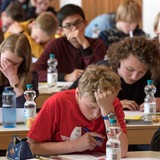 Schüler sitzen in einem Raum und schreiben 