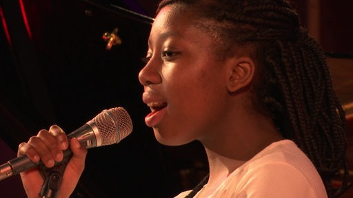 Eine Schülerin singt auf der Bühne.