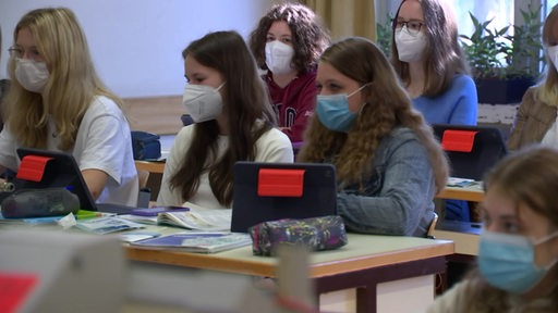 Schülerinnen während der Coronapandemie im Präsenzunterricht in einem Klassenzimmer.
