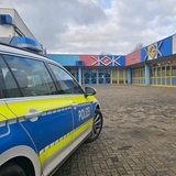 Ein Polizeiauto steht auf einem leeren Schulhof.