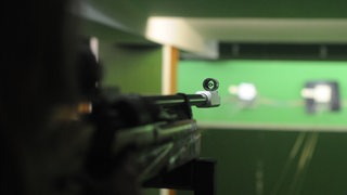 Ein Schütze auf einem Schießstand zielt auf eine Zielscheibe (Symbolbild)