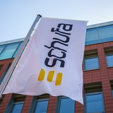 Eine Flagge mit dem Firmenlogo flattert vor dem Geschäftssitz der Schufa Holding AG.