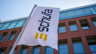 Eine Flagge mit dem Firmenlogo flattert vor dem Geschäftssitz der Schufa Holding AG.