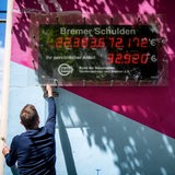 Ein Mitarbeiter des Steuerzahlerbundes hantiert an der Bremer Schuldenuhr