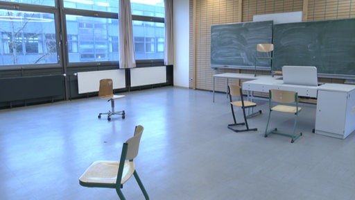 In einem Klassenzimmer sind Stühle und Tafeln zu sehen.