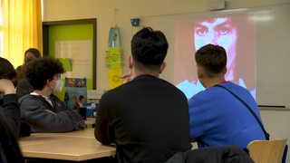 Schüler*innen schauen in einem Klassenzimmer einen Film. 