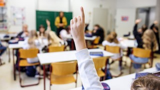 Schülerinnen und Schüler melden sich in einem Klassenraum.